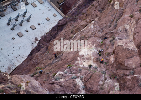 Hoover Dam on the Nevada Arizona border.  Workers on ropes working on cliff face.