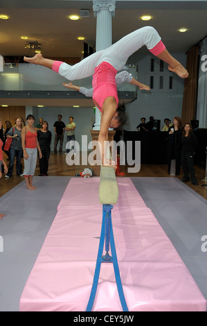 Stella McCartney Adidas London Ready to Wear Spring Summer Females on gymnastics balance beam, in an inverted pose Stock Photo