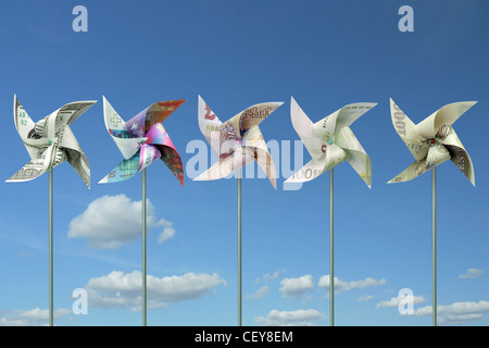 Toy windmills cut from five major world currency banknotes over blue sky Stock Photo