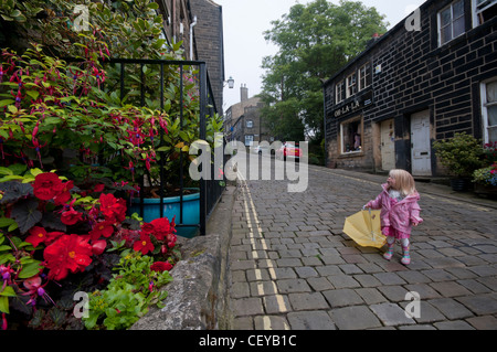 Young child with umbrella in Haworth High Street. Stock Photo