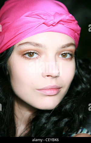 Sue Stemp New York Ready to Wear Spring Summer Head shot of dark haired female long curly hair wearing pink headscarf, bronze Stock Photo