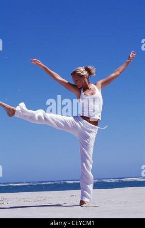 Female on beach kicking leg high up in air Stock Photo