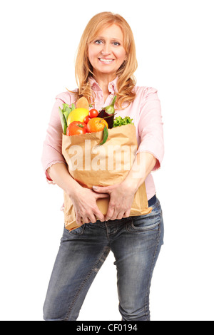 A smiling woman holding a paper bag full of groceries isolated on white background Stock Photo