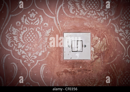 Dirty light switch on the old painted wall with floral pattern Stock Photo