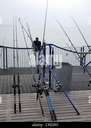 Sea angling. An angler with lots of fishing rods on the pier at