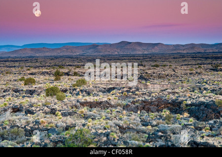 Moon setting down at sunrise over Carrizozo Malpais lava field, Valley of Fires, near Carrizozo, New Mexico, USA Stock Photo