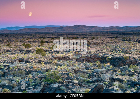 Moon setting down at sunrise over Carrizozo Malpais lava field, Valley of Fires, near Carrizozo, New Mexico, USA Stock Photo