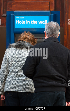 People using local cash Barclays 'Hole in the Wall' cash machine, England, UK. Stock Photo