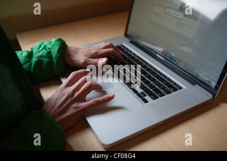 Close up of forty year old woman typing on lap top computer keyboard, with window light. Stock Photo