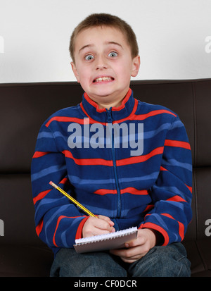 Young boy writes on some blank plan white paper Stock Photo