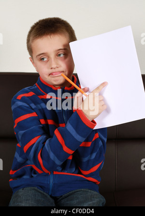 Young boy writes on some blank plan white paper Stock Photo