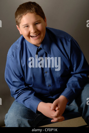 A Caucasian fourteen year old boy, who is sitting down and smiling at the viewer. Stock Photo