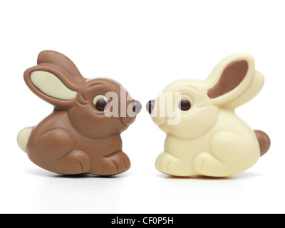 Two cute milk and white chocolate bunnies sitting nose to nose isolated on white background Stock Photo