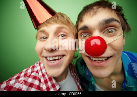 Two crazy guys making faces at camera on fool’s day, isolated on green background Stock Photo