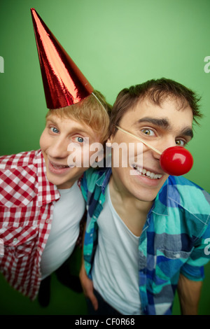 Fools day party in full swing, guys smiling and looking funny, isolated on green background Stock Photo