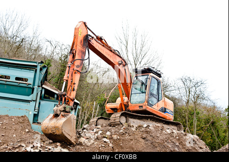 Orange digger on mound on building site. Stock Photo