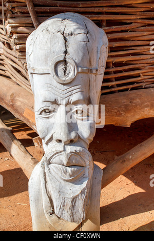 African carved wooden statue in front of dwelling Stock Photo