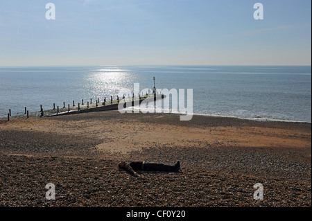 Man asleep on the shingle in warm winter sunshine on Hove beach and seafront Sussex UK Stock Photo