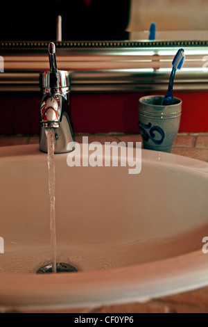Sink with tap water and a toothbrush