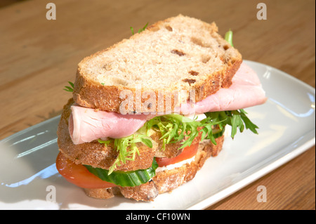 A triple decker ham and salad sandwich made with granary bread on a white plate. Stock Photo