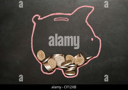 Pile of real pound coins lying within a chalk illustration of a piggy bank on a blackboard Stock Photo