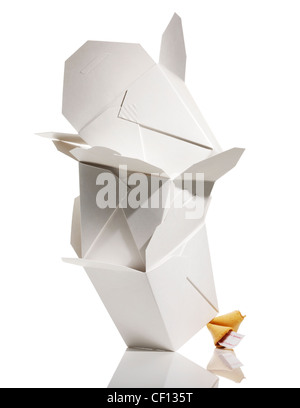 Leaning stack of Chinese takeout boxes balanced on a fortune cookie. Stock Photo