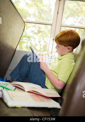 Caucasian boy doing homework on school bus Stock Photo