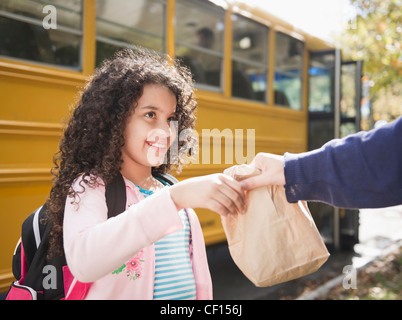 Mother handing daughter sack lunch Stock Photo