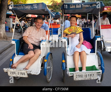 Mature couple of tourists in rickshaws touring the old town, Hanoi, Vietnam Stock Photo