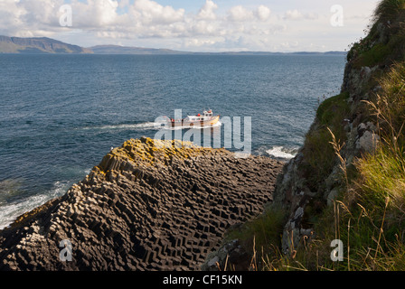 Boat departing from the Isle of Staffa on a site seeing sea cruise with Ulva in the background Stock Photo