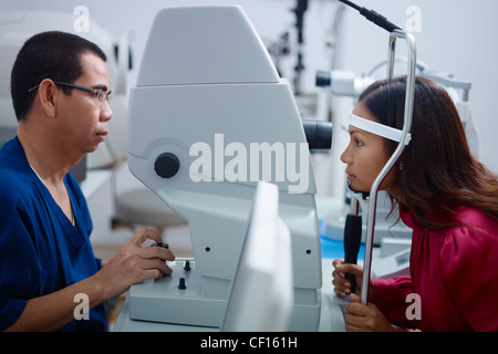 Asian doctor at work during eyesight exam to adult woman in hospital. Side view