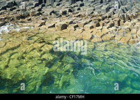 Hexagonally jointed basalt columns beside Fingal's cave on the Isle of Staff of Mull in Scotland partially covered with water Stock Photo