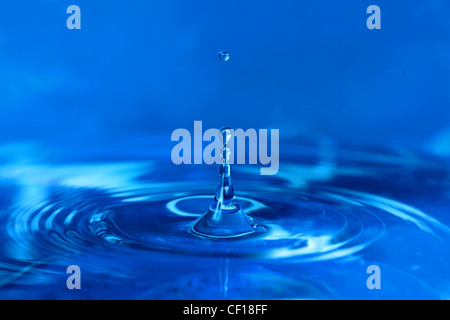 Water drops falling on surface creating ripples Stock Photo