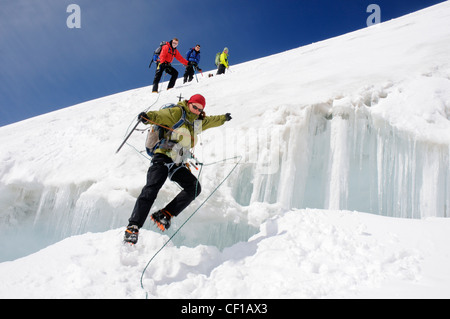 A lady climber leaping a large crevasse on the traverse on Monte Rosa in Switzerland Stock Photo
