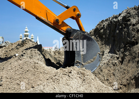 An arm of a JCB, earth mover digging into sand Stock Photo