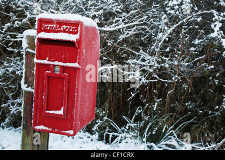 A small rural red post box covered in snow. Stock Photo
