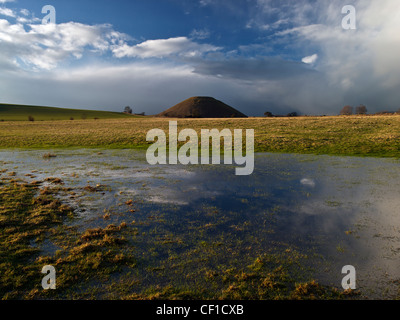 Silbury Hill, the tallest prehistoric human-made mound in Europe, viewed across a flooded field. Stock Photo