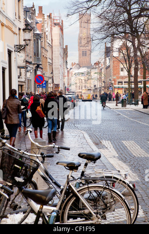 A street view of people walking along Steenstraat with the Belfry in the background Stock Photo