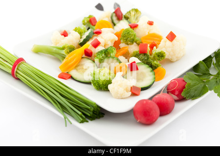 boiled and raw vegetables on white plate Stock Photo