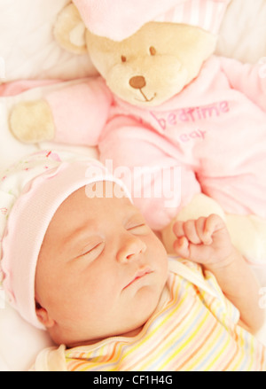 Cute little baby sleeping in pink pajama with teddy bear toy Stock Photo