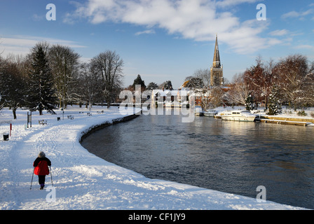 A woman walking along a snow covered path by the River Thames at Abingdon. Stock Photo
