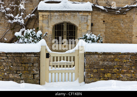 Snow covered gate and path leading to the front door of Silver Street House, a stone built Cotswold village house in South Cerne Stock Photo