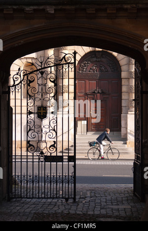 A cyclist travelling along the High Street past a gateway at the end of Logic Lane Stock Photo