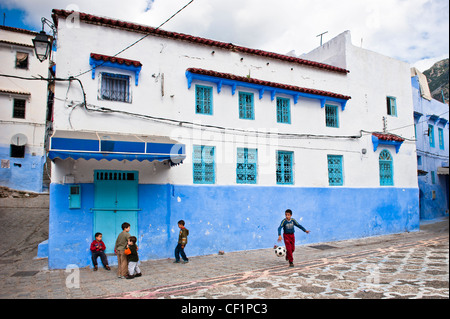 Kids playing footbal in the blue walled old medina of Chefchaouen, Morocco Stock Photo