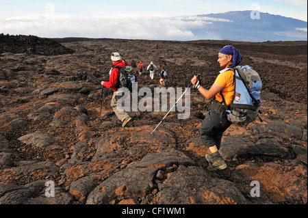 Hikers in the Hawaii Volcanoes National Park walking on cooled lava, Mauna Loa Volcano, Big Island, Hawaii, USA Stock Photo