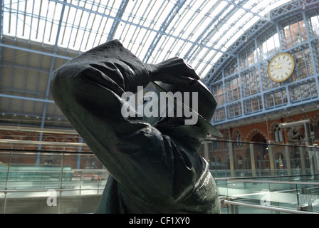 A statue of poet John Betjeman by Martin Jennings at St. Pancras International station, with the famous clock in the background. Stock Photo