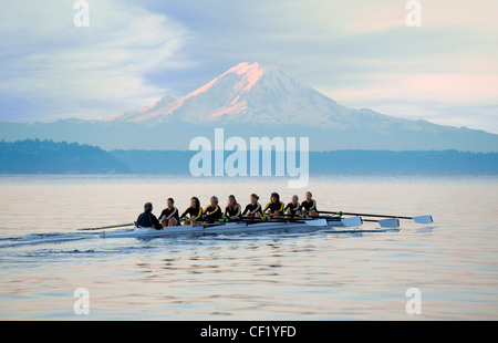 Team rowing boat in bay Stock Photo