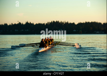 Team rowing boat in bay Stock Photo