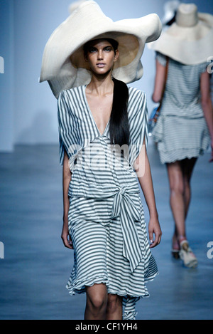 Gibo Milan Spring Summer Model long black hair in pony tail down one shoulder wearing very large wide brimmed white straw hat Stock Photo