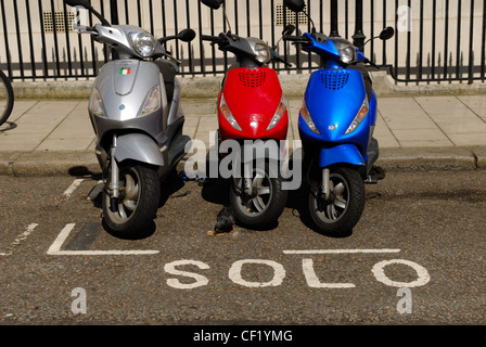 Silver, red and blue scooters parked next to each other in a parking bay in a central London street. Stock Photo